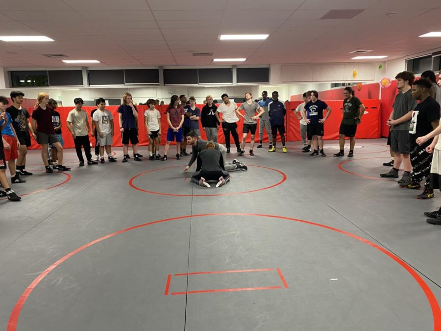 Coach Cale Holt demonstrates a wrestling move to the team. They hope to send multiple wrestlers to state this year.