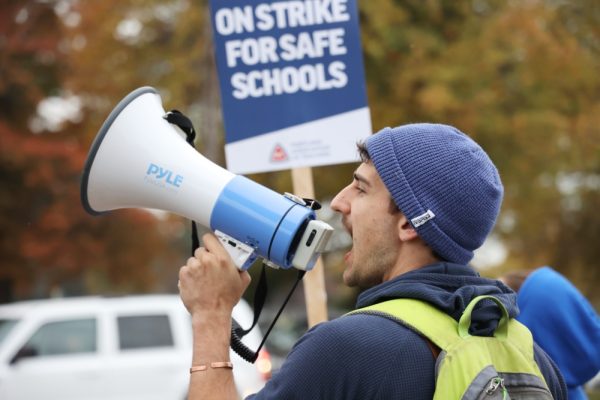 Science teacher Ethan Kane leads strike chants across the street from the school. he raises the spirits of bystanders.