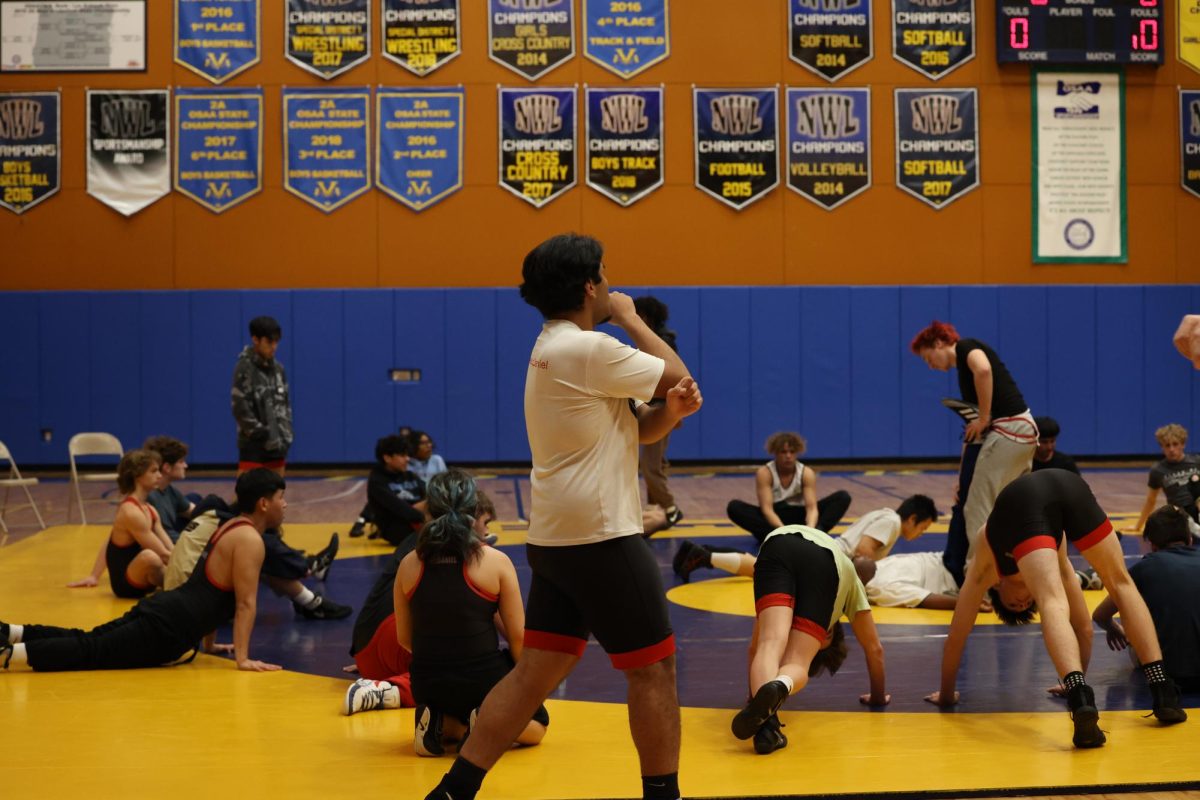 Junior Miguel Navarro watching the JV wrestling team prep for a meet. Having youth in a sports program is crucial to a programss success.