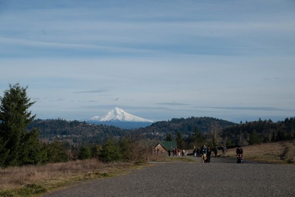 A view of Mt. Hood and the Gresham buttes from a wide path at Powell Butte Nature Park. Many other people are seen enjoying the hike and the view on a warm February day.