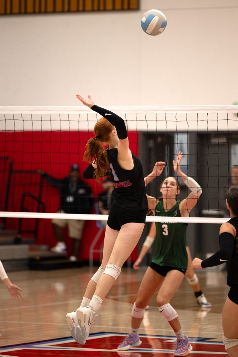 Senior Anna Gladwin jumps up to spike down the ball. Her defender does her best to defend it.