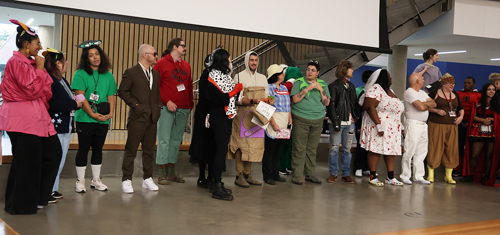 All staff costume contest participants line up together in front of the commons. The winners all receive small orange goodie bags as a prize for their unique costumes, while the other staff members are gifted candy as a participation award. 