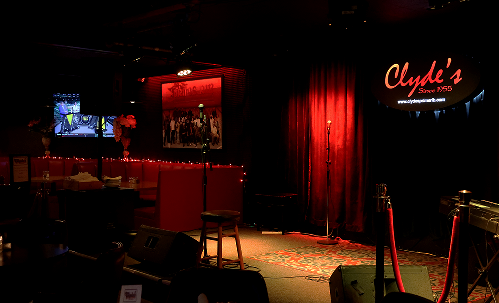 Clydes seating area near bar, with stage and microphone. The spotlights above create a dramatic look.