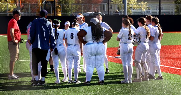 The McDaniel varsity softball team huddles up between innings. These huddles are essential to the team's bond and ability to work together on the field. 