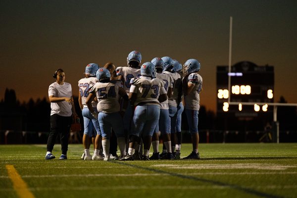 The team gathers to talk about the upcoming play during a time out. The team listens closely as their coach instructs them.