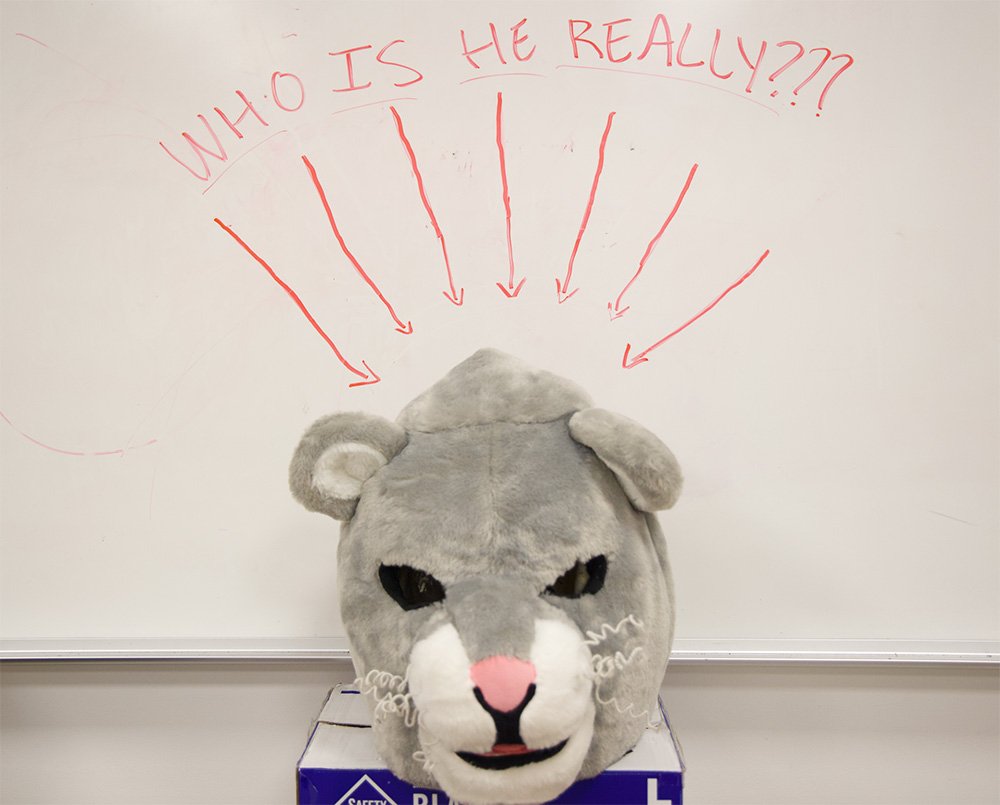 Leo's mascot head is pictured with question marks surrounding his identity. His true identity has been investigated by many, but few have succeeded in discovering who he really is.