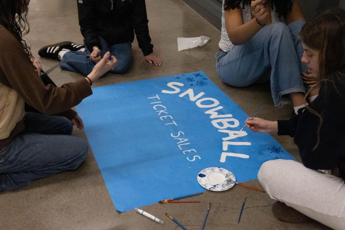 Leadership students Roxy Meyers, Abby Davidson, and Nila Kwa creating a poster for ticket sales. The posters include ticket costs and dates to buy tickets.