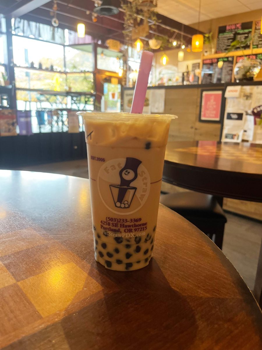 A honey lavender milk tea rests on a table. The table is multi-use, doubling as a chess table.