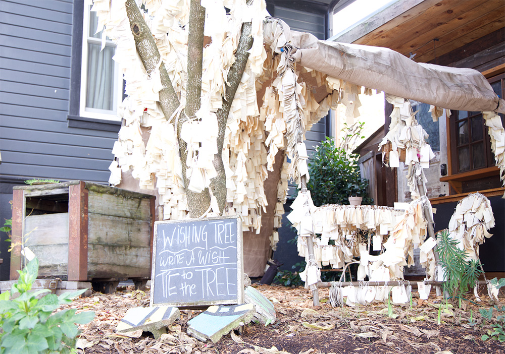 The Portland North Williams Avenue wishing tree features simple instructions on a blackboard leaning on the trunk. Although the tree is located in a front yard, it is still open to the public. 
