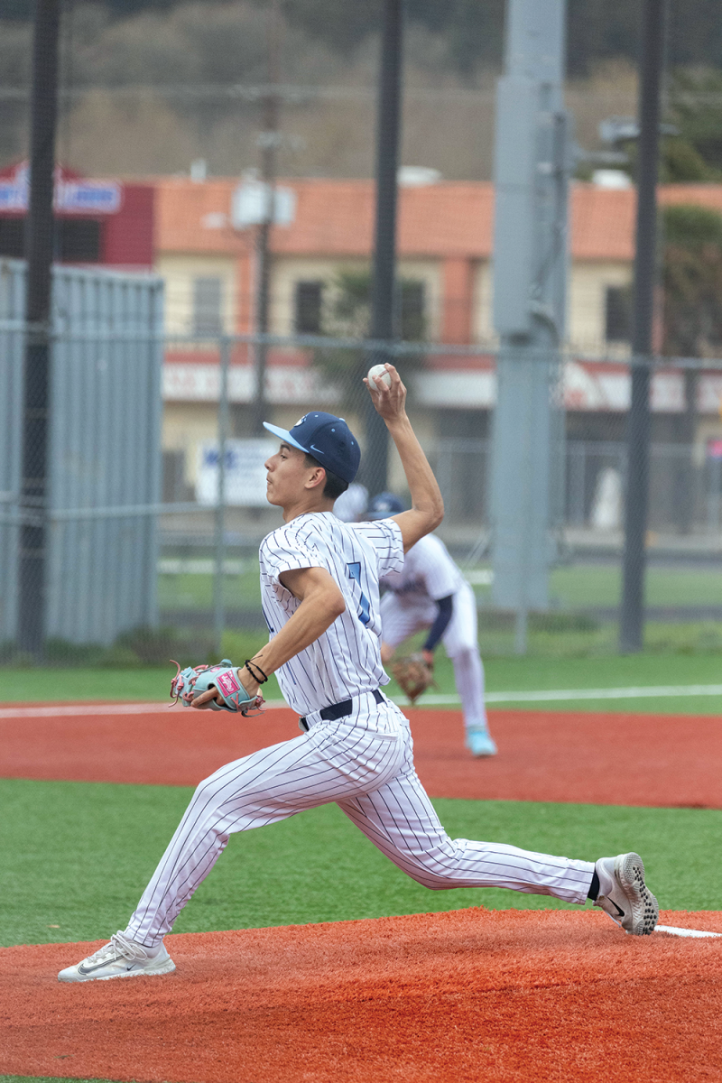 Junior Henry Campos pitches the ball. Campos winds up his arm as he prepares to release the pitch.