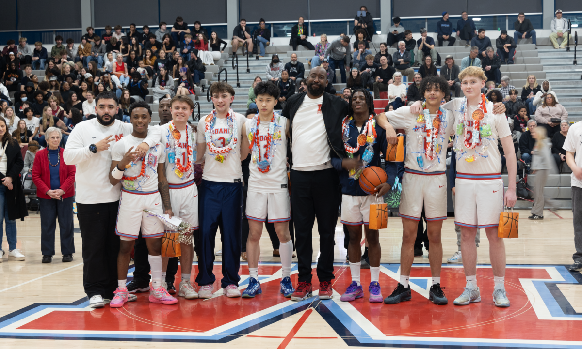 The varsity senior boys stand with coaches Emiliano Alvarado (left) and Arron Boone (center). The players came out with their families while the crowd celebrated the boys on their last night, which was a win against Franklin.