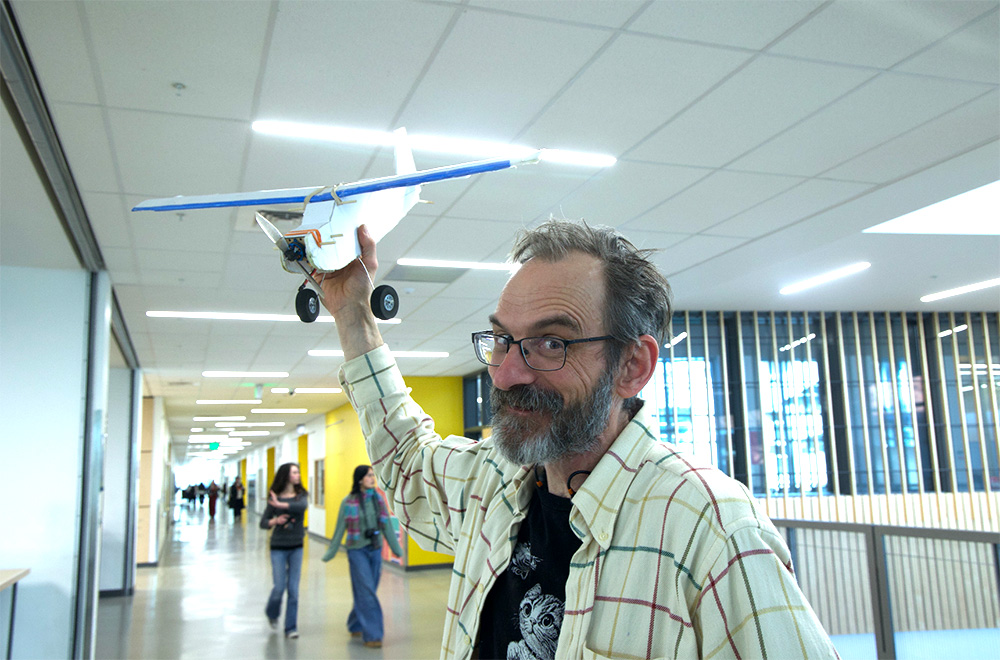 Aerospace engineering teacher Christopher Moore prepares to hand-launch a plane model. Moore describes his plane as cool.