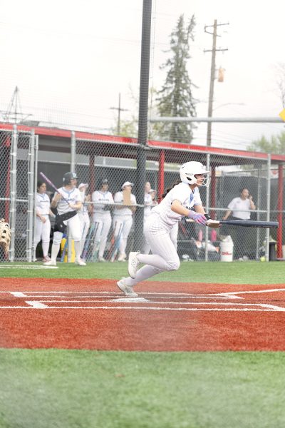 Freshman Brylee Scott runs to first base after a hit. Scott's teammates cheer her on from behind.